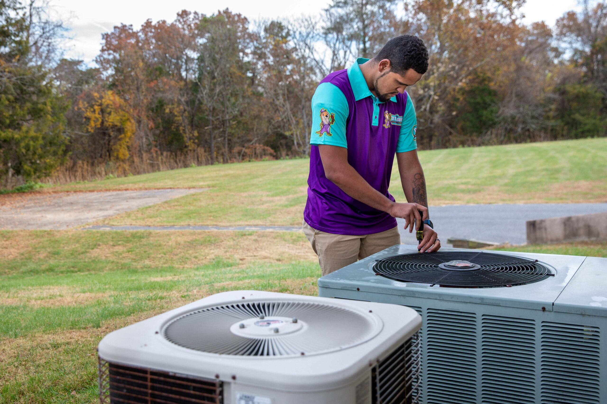 An HVAC technician evaluating an Air Conditioning unit sitting outside on the grass.