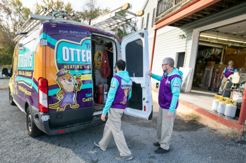 Two Otter Guys employees standing at the back of the work van.