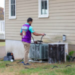 Homeowner Guide: How Do I Know If My HVAC System Needs Repair? An Otter Employee washing an HVAC system.
