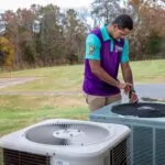 An HVAC technician evaluating an Air Conditioning unit sitting outside on the grass.