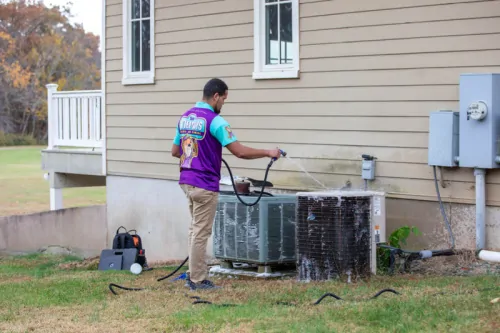 An Otter Guys employee washing a HVAC system.